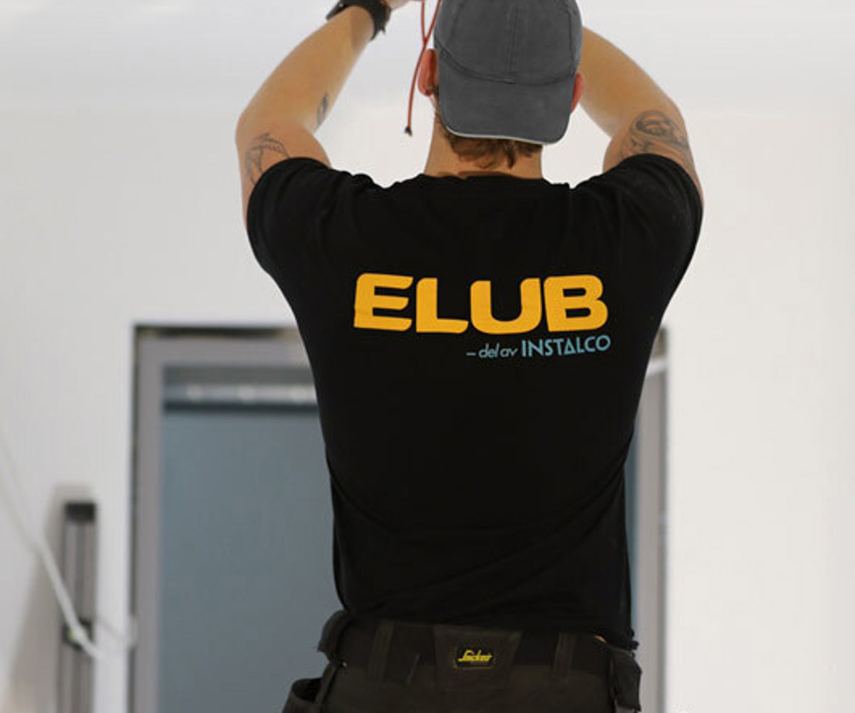 Bild på en elektriker som drar el med en Elub-tröja på sig. Elub är din proffsiga elektriker i Växjö